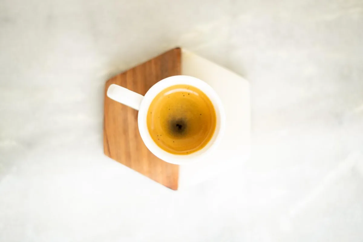 Espresso sobre posavasos de madera y mármol