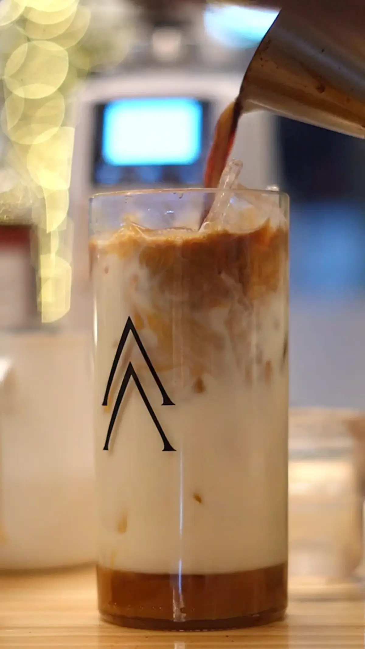 Espresso vertido sobre un iced latte en un vaso Λ